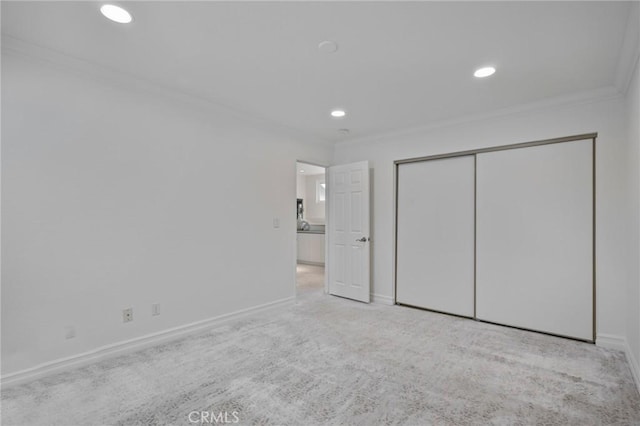 unfurnished bedroom with crown molding, light colored carpet, and a closet