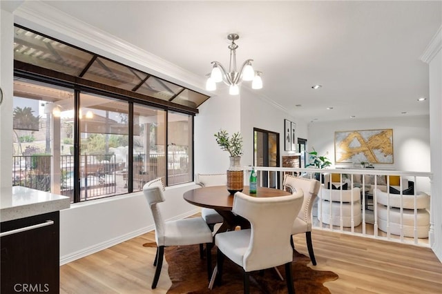 dining area featuring an inviting chandelier, crown molding, and light hardwood / wood-style flooring