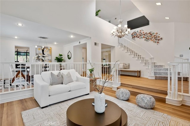 living room featuring a notable chandelier, a towering ceiling, and wood-type flooring