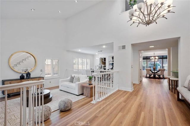 living room with a towering ceiling, wood-type flooring, and a notable chandelier