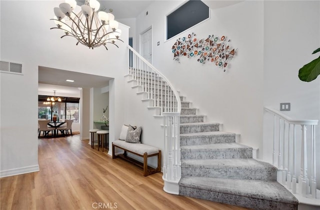 stairway with hardwood / wood-style flooring, a high ceiling, and a chandelier