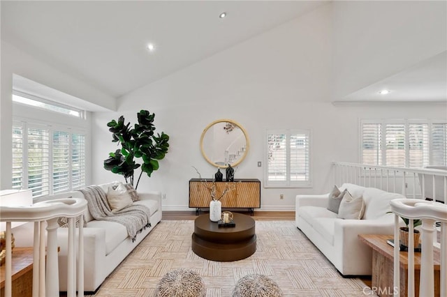 living room featuring plenty of natural light, light hardwood / wood-style floors, and high vaulted ceiling