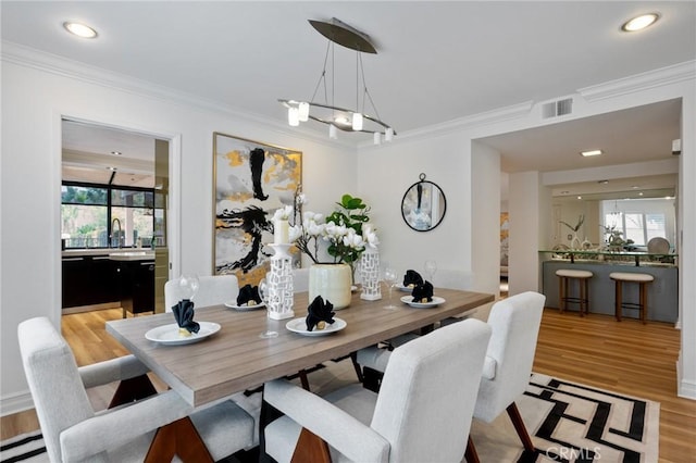 dining area featuring a baseboard radiator, ornamental molding, an inviting chandelier, and light wood-type flooring