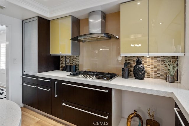 kitchen featuring backsplash, ornamental molding, stainless steel gas cooktop, light hardwood / wood-style floors, and wall chimney range hood