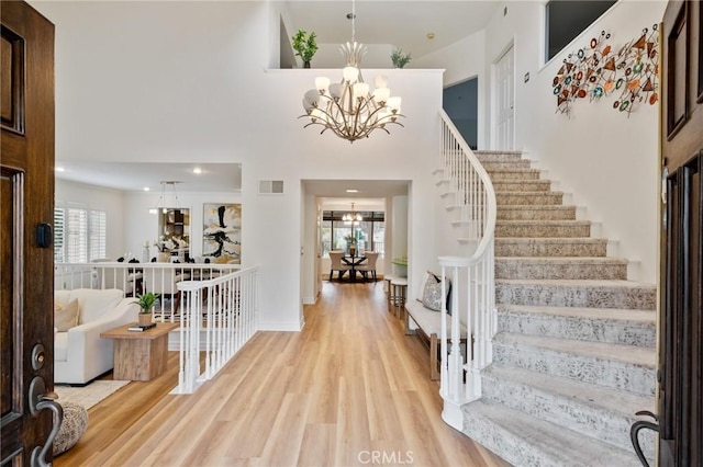 foyer entrance with a notable chandelier, light hardwood / wood-style flooring, and a high ceiling