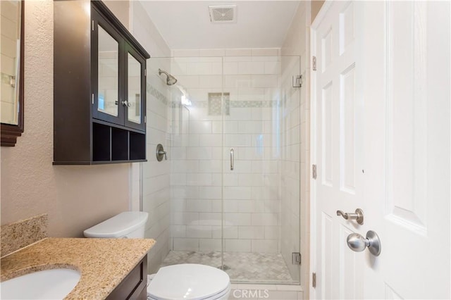 bathroom with vanity, a shower with shower door, and toilet