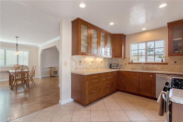 kitchen featuring pendant lighting, sink, backsplash, light stone countertops, and gas range