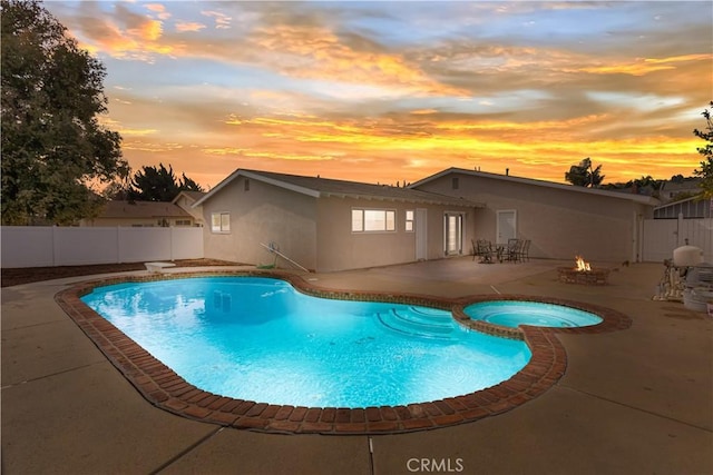 pool at dusk featuring a fire pit, a patio, and an in ground hot tub