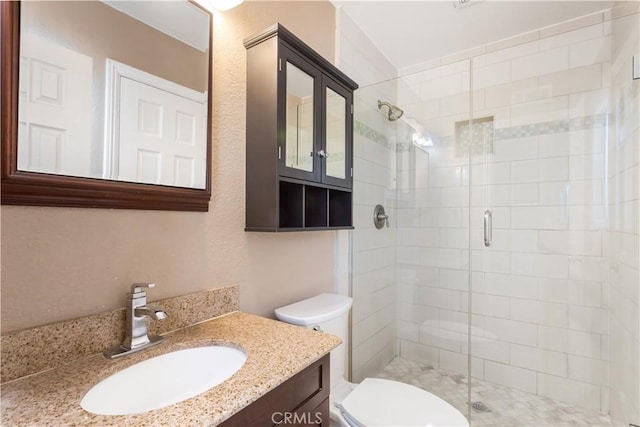 bathroom with a shower with door, vanity, and toilet