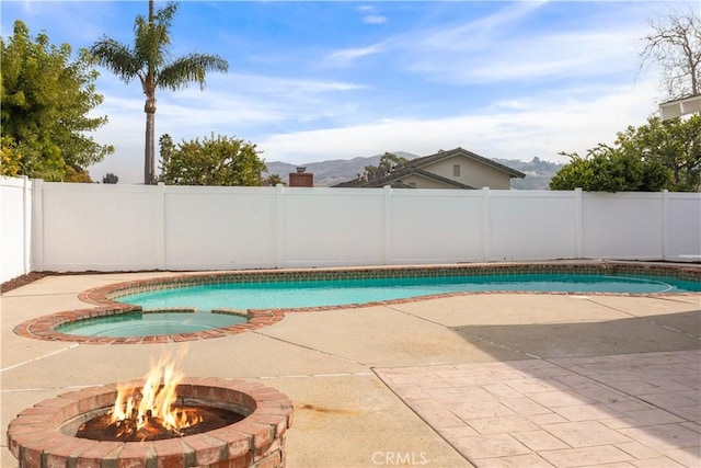 view of swimming pool with a mountain view, a patio area, and a fire pit