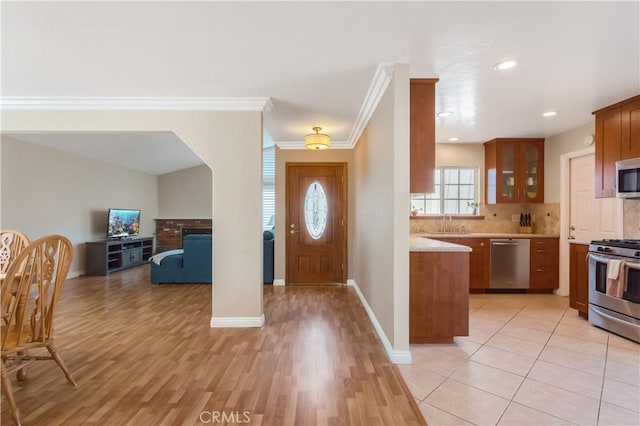 kitchen with sink, light hardwood / wood-style flooring, ornamental molding, stainless steel appliances, and backsplash