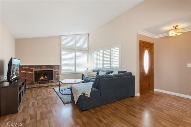 living room featuring crown molding, lofted ceiling, hardwood / wood-style floors, and a brick fireplace