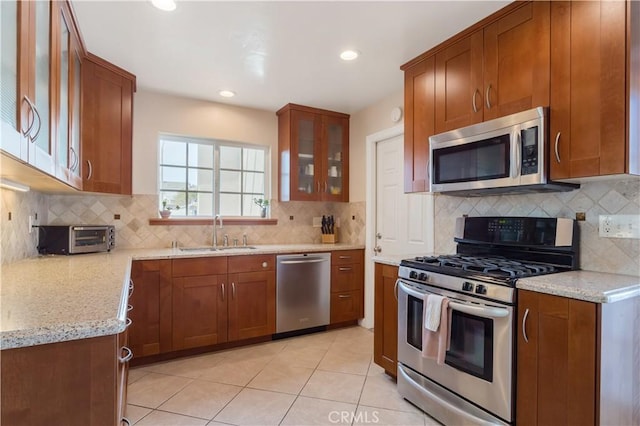 kitchen with light stone counters, sink, backsplash, and stainless steel appliances