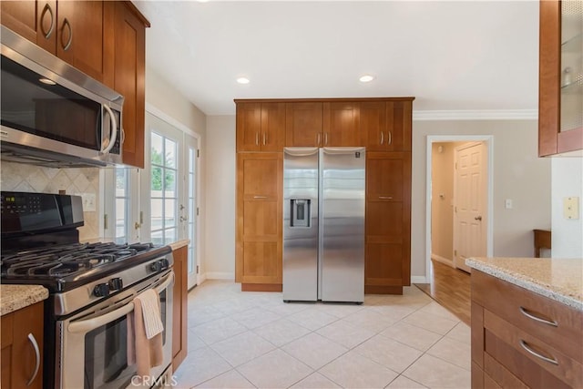 kitchen featuring light tile patterned floors, stainless steel appliances, light stone counters, ornamental molding, and decorative backsplash