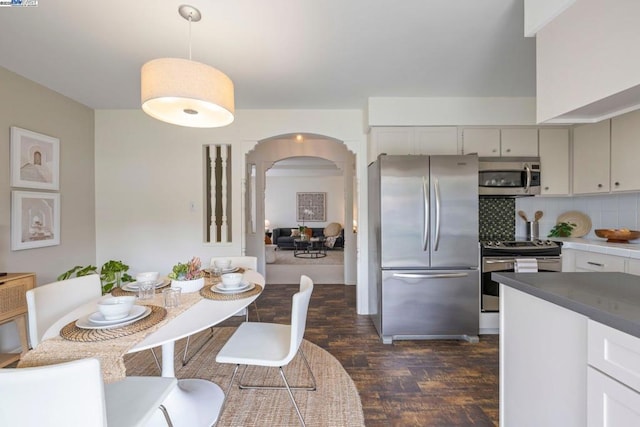 kitchen with dark wood-type flooring, decorative light fixtures, stainless steel appliances, decorative backsplash, and white cabinets