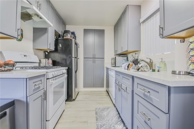 kitchen with white appliances, sink, gray cabinets, and light hardwood / wood-style floors