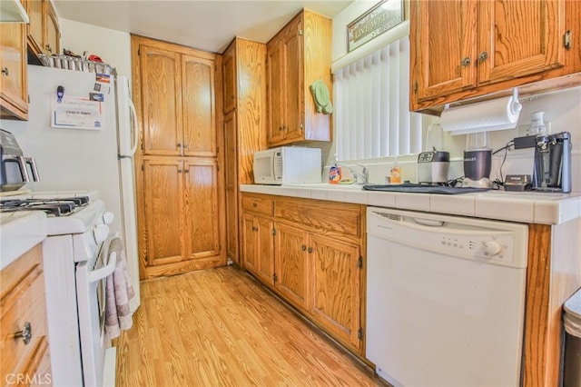 kitchen with white appliances, tile countertops, and light hardwood / wood-style floors