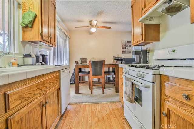 kitchen featuring white appliances, plenty of natural light, light hardwood / wood-style flooring, and a textured ceiling