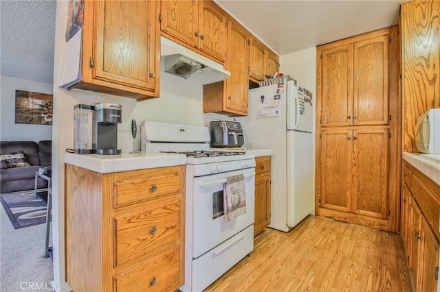 kitchen featuring tile countertops, a textured ceiling, white appliances, and light hardwood / wood-style floors