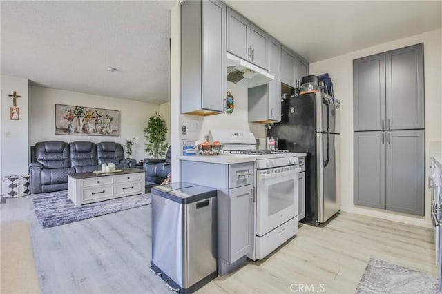 kitchen with light hardwood / wood-style flooring, stainless steel fridge, gray cabinets, refrigerator, and white range with gas cooktop