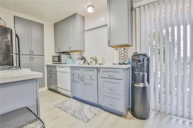 kitchen featuring appliances with stainless steel finishes, gray cabinetry, and light wood-type flooring