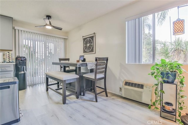 dining area with an AC wall unit, light wood-type flooring, and ceiling fan