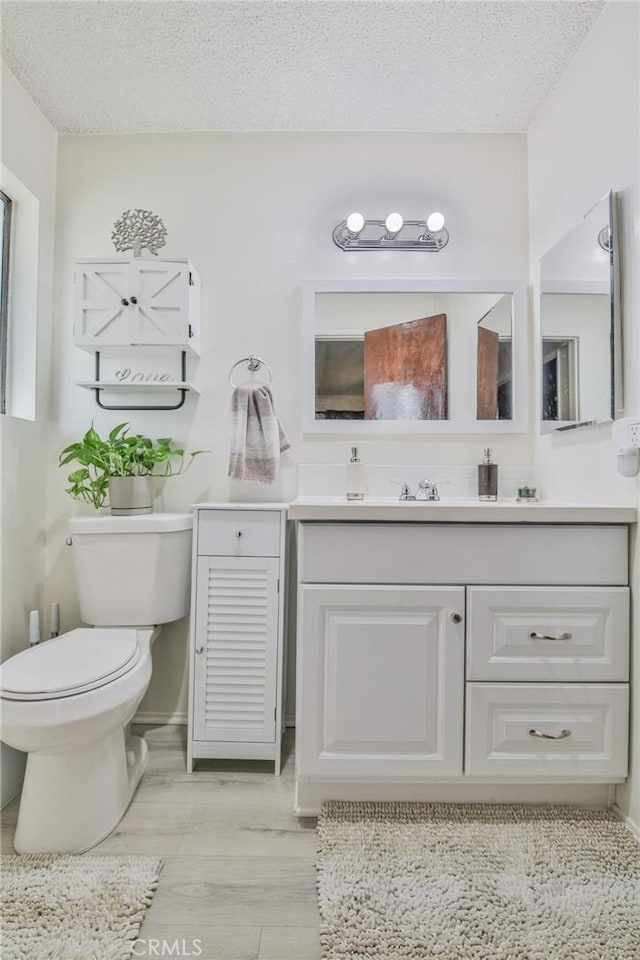 bathroom with vanity, toilet, and a textured ceiling