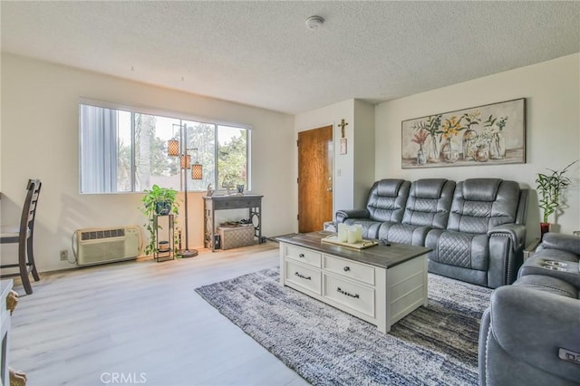 living room with wood-type flooring, an AC wall unit, and a textured ceiling