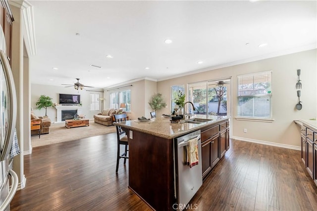 kitchen with a breakfast bar, an island with sink, sink, stainless steel appliances, and dark brown cabinets