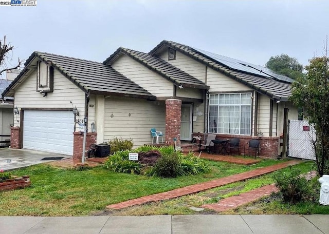 single story home with a garage, a front lawn, and solar panels