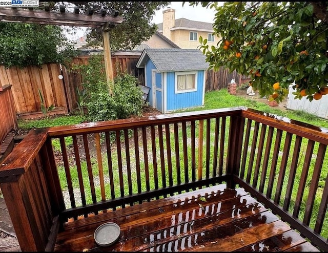 wooden terrace featuring a lawn and a storage shed