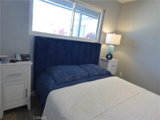 bedroom with multiple windows and dark wood-type flooring