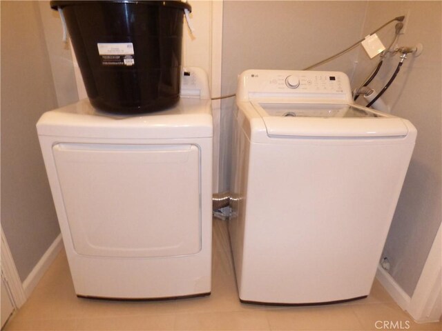 laundry area with light tile patterned flooring and washing machine and dryer