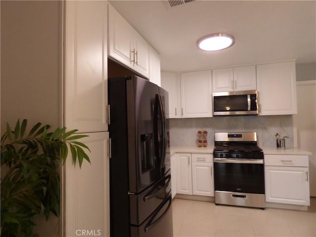 kitchen with decorative backsplash, white cabinets, and appliances with stainless steel finishes