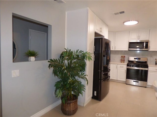 kitchen with stainless steel appliances, light tile patterned flooring, and white cabinets