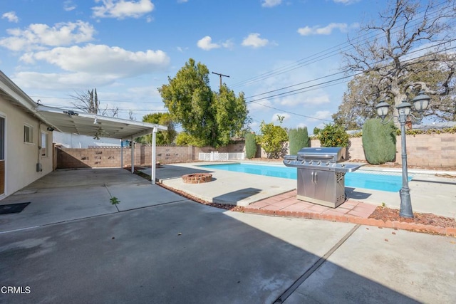 view of swimming pool featuring area for grilling and a fire pit