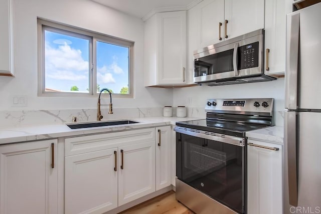 kitchen featuring white cabinetry, appliances with stainless steel finishes, sink, and light stone counters