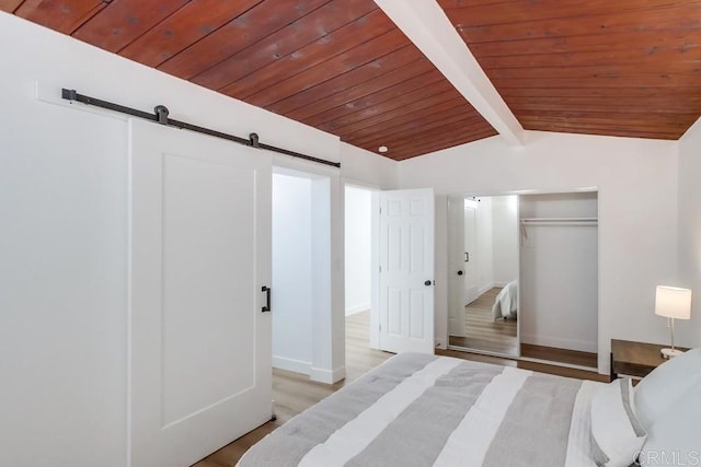 bedroom featuring wood ceiling, light hardwood / wood-style flooring, lofted ceiling with beams, and a barn door