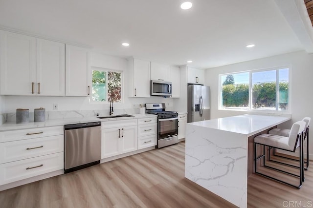 kitchen with sink, a breakfast bar area, white cabinets, and appliances with stainless steel finishes