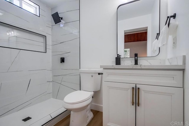 bathroom with vanity, tiled shower, hardwood / wood-style floors, and toilet