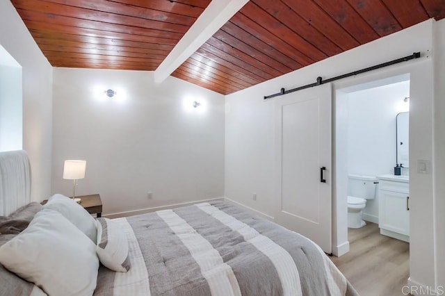 bedroom with lofted ceiling with beams, a barn door, connected bathroom, and wood ceiling