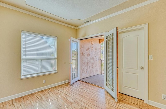 entryway with light hardwood / wood-style flooring, ornamental molding, and a textured ceiling