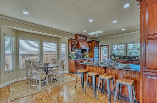 kitchen with sink, crown molding, a skylight, and light hardwood / wood-style floors