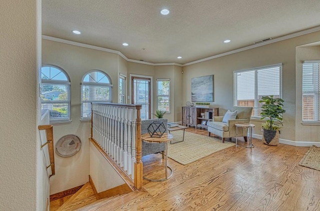 living area with ornamental molding, light hardwood / wood-style flooring, and a textured ceiling