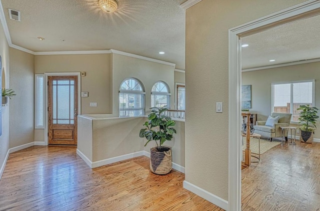 entrance foyer with crown molding, light hardwood / wood-style flooring, and a textured ceiling