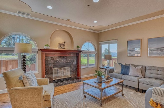 living room with ornamental molding, a premium fireplace, hardwood / wood-style floors, and a textured ceiling