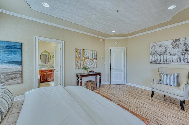 bedroom featuring crown molding, ensuite bathroom, a textured ceiling, and light wood-type flooring