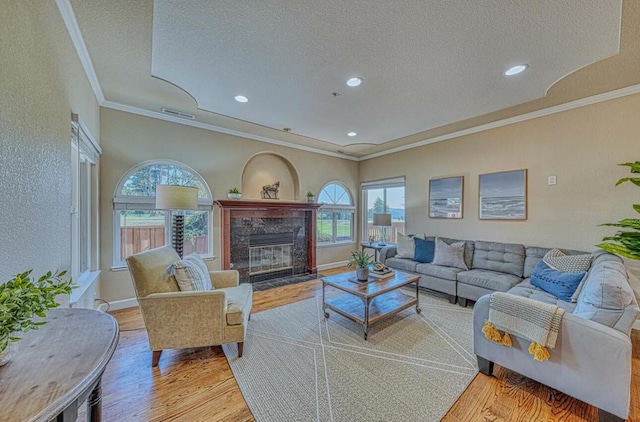 living room with a healthy amount of sunlight, a fireplace, light hardwood / wood-style flooring, and a textured ceiling