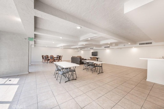 dining space featuring light tile patterned flooring, beam ceiling, and a textured ceiling