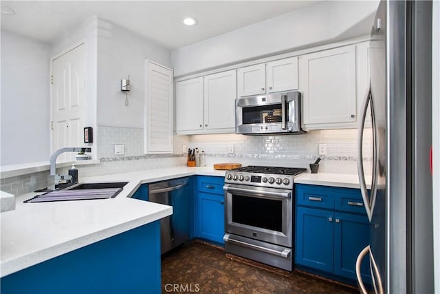 kitchen featuring appliances with stainless steel finishes, blue cabinets, sink, white cabinets, and backsplash